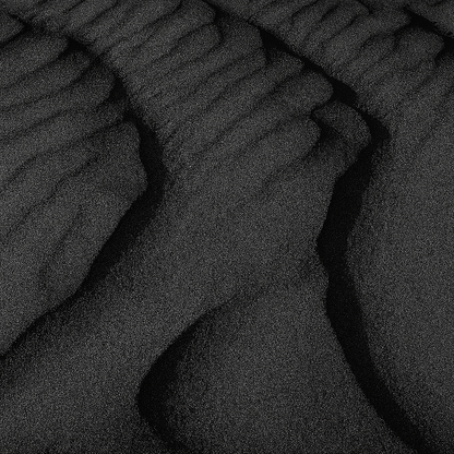 Textured black volcanic sand resembling waves, showcasing the natural beauty of Iceland's landscape.